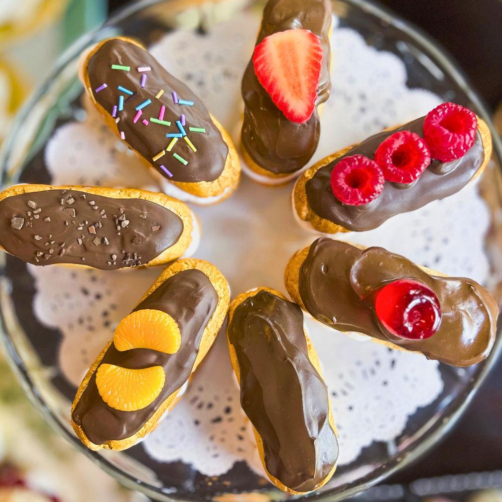 Decorative chocolate pastries with fruit toppings on a glass plate.