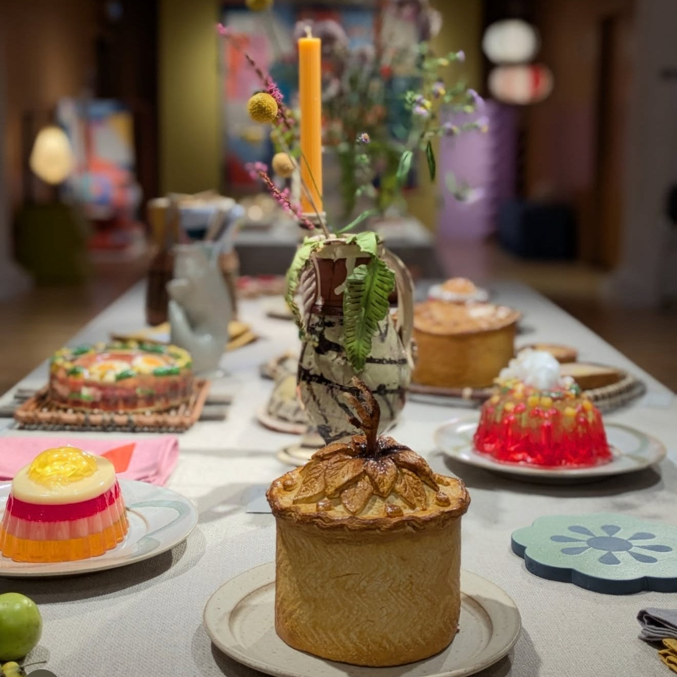 Dessert table with various pastries and a candle in a decorative holder.