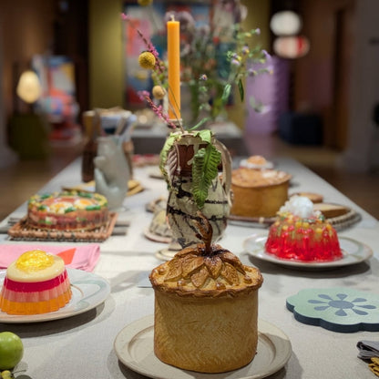 Dessert table with various pastries and a candle in a decorative holder.