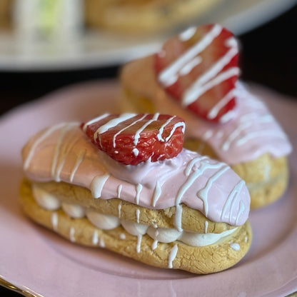 Fake Eclairs with strawberry and cream on a pink plate