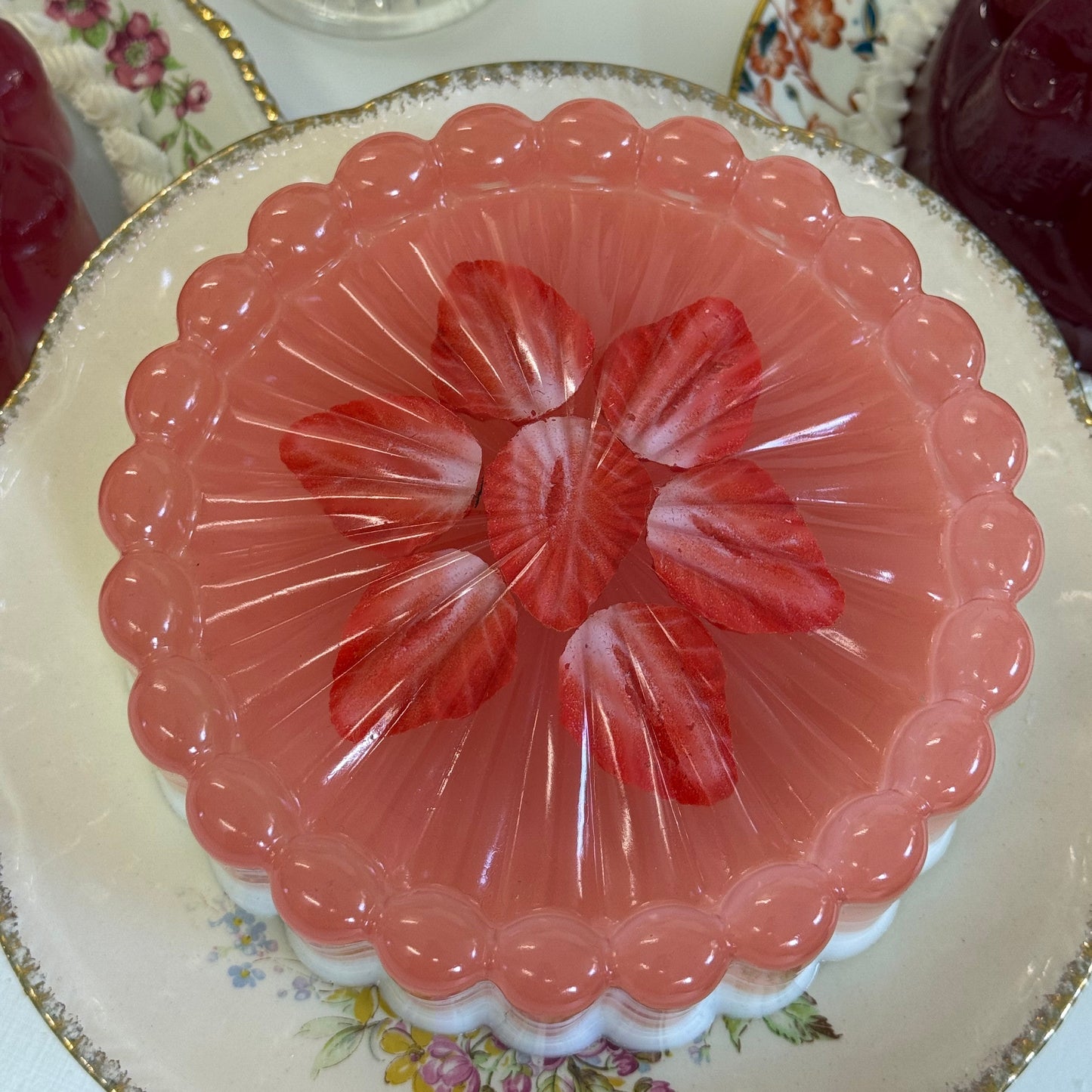 Pink jelly on a glass dish with floral design on a floral-patterned plate