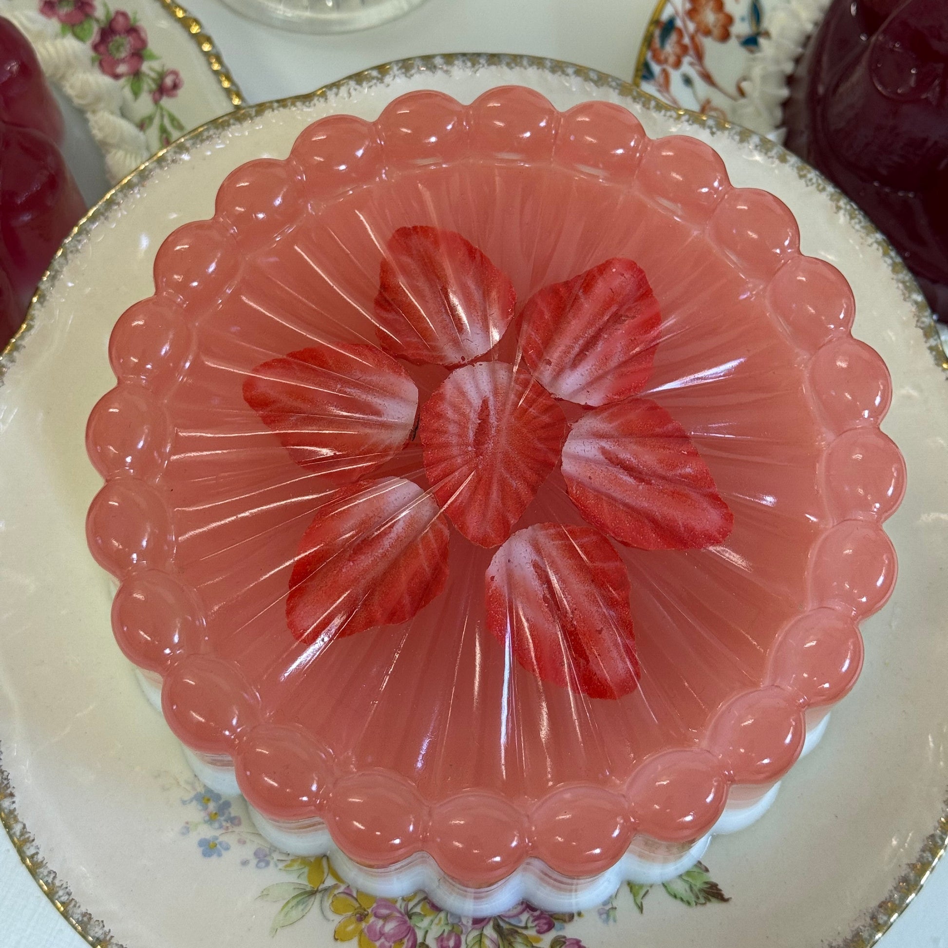 Pink jelly on a glass dish with floral design on a floral-patterned plate