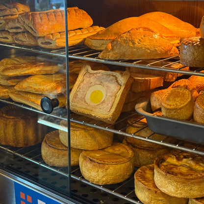 Display case with various baked goods including pies and bread.